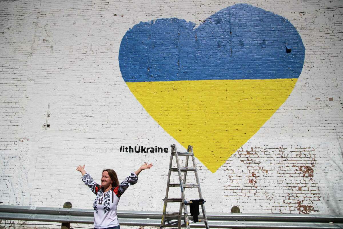 Iryna Petrovska Marchiano, president for Ukrainian American Cultural Club of Houston poses for a photo in front of a mural in downtown Houston. The mural is in support of Ukraine as the country is attacked by Russia, Monday, Feb. 28, 2022, in Houston. The artist working on the mural is Shelbi Nicole.