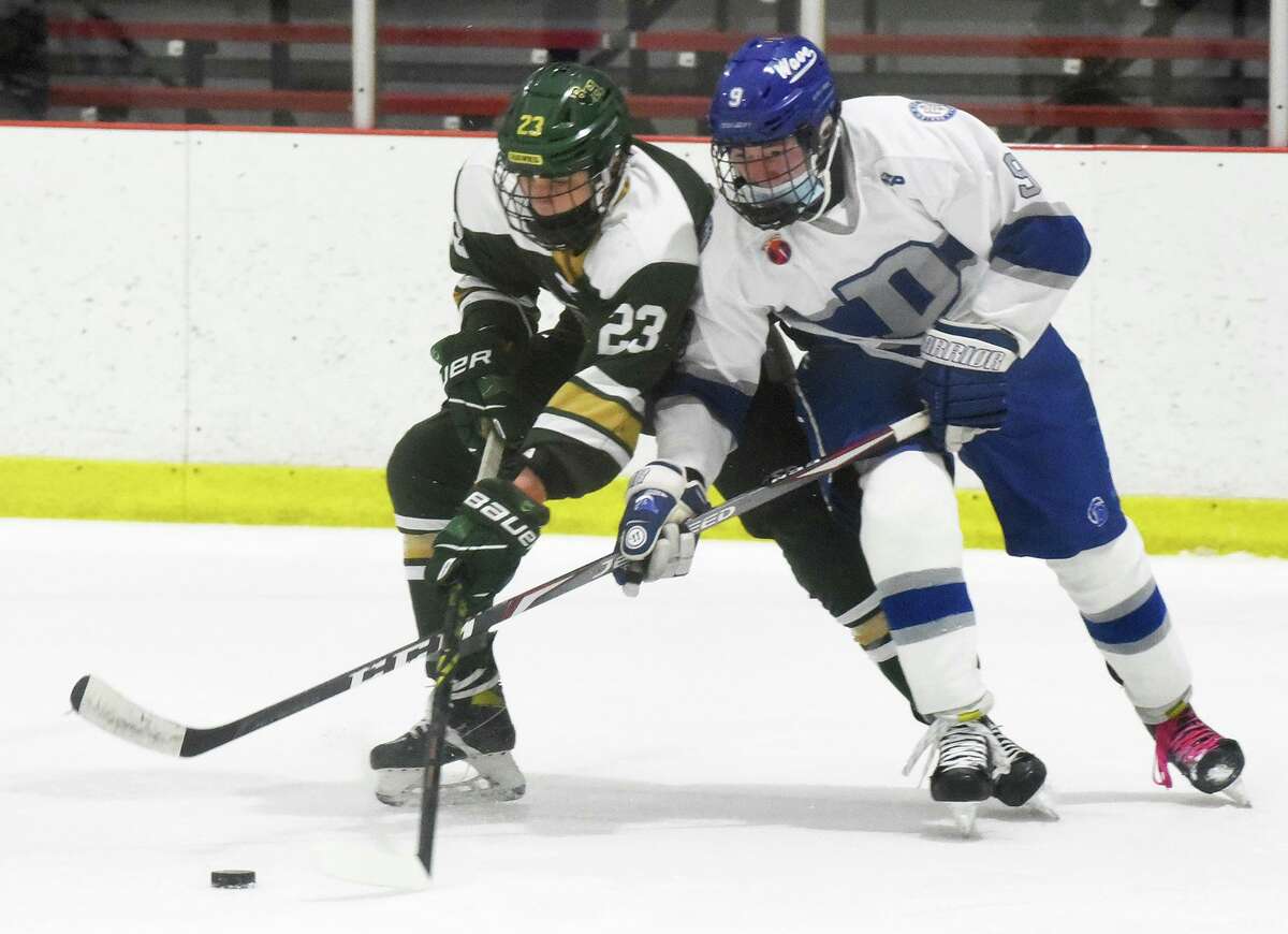 Darien's Arthur Devillers (9) and Bishop Hendricken's Colton Whitfield (23) battle during a boys ice hockey game at the Darien Ice House on Saturday, Jan. 8, 2022.