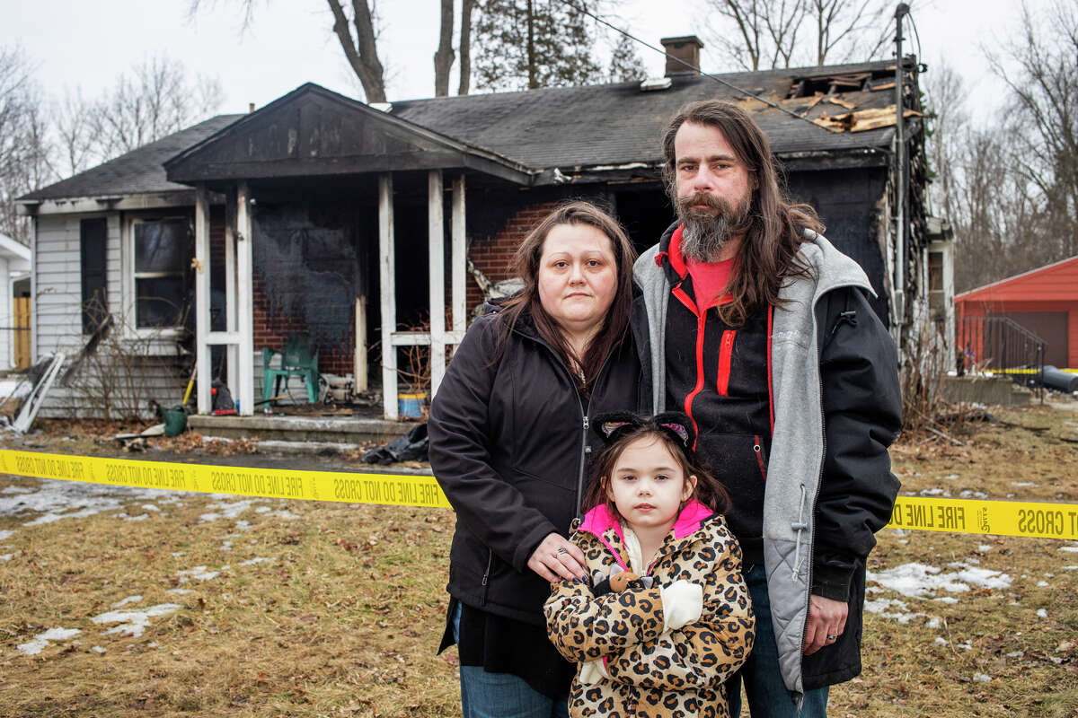 Denise Wittbrodt Fry, left, Patrick Fry, right, and their daughter Mia Hinkley, 9, stand in front of their home on Parsons Court in Midland, which was destroyed in a fire on Saturday, Feb. 26, 2022. The fire also claimed the lives of three of the family's pet cats.