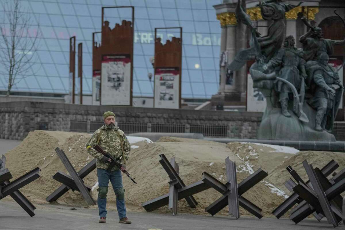 An armed man stands near a barricade during an air raid alarm in Maidan Square, in Kyiv, Ukraine, Tuesday, March 1, 2022. Russian strikes pounded the central square in Ukraine’s second-largest city and other civilian targets, and a 40-mile convoy of tanks and other vehicles threatened the capital. (AP Photo/Vadim Ghirda)