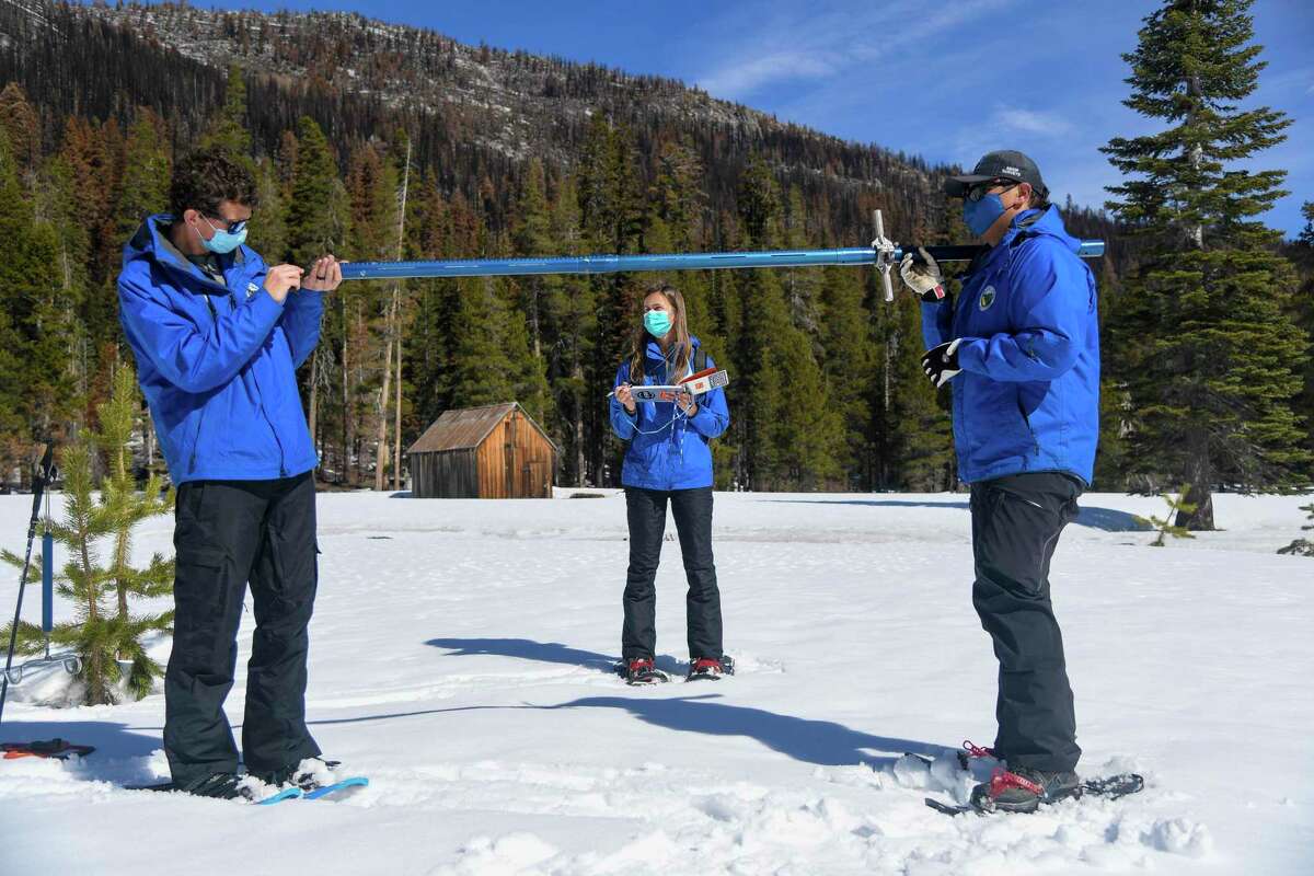 In this photo provided by the California Department of Water Resources Nick Ellis, left, Lauren Alkire and Sean de Guzman, manager of snow surveys and water supply forecasting, conduct the third snow survey of the season at Phillips Station near Echo Summit on Tuesday. California’s winter mountain snowpack is far below average after two historically dry months that reversed the gains from storms late last year