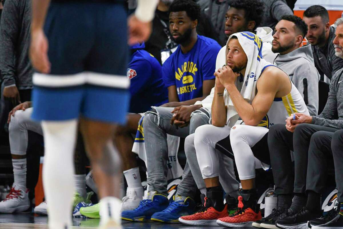 Golden State Warriors guard Stephen Curry, right with a towel, and forward Andrew Wiggins check the scoreboard in the final minutes of the team's NBA basketball game against the Minnesota Timberwolves on Tuesday, March 1, 2022, in Minneapolis. The Timberwolves won 129-114. (AP Photo/Craig Lassig)