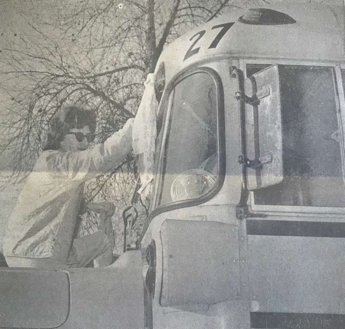 Mrs. Robert Randall climbs on the hood of her bus to polish its wide-view windows while waiting her turn at the gasoline pumps at Midland Public Schools bus garage. November 1963