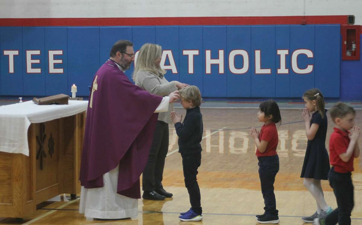 Father Zeljko Guberovic marks the forehead of a Manistee Catholic Central student during Ash Wednesday Mass at the school.
