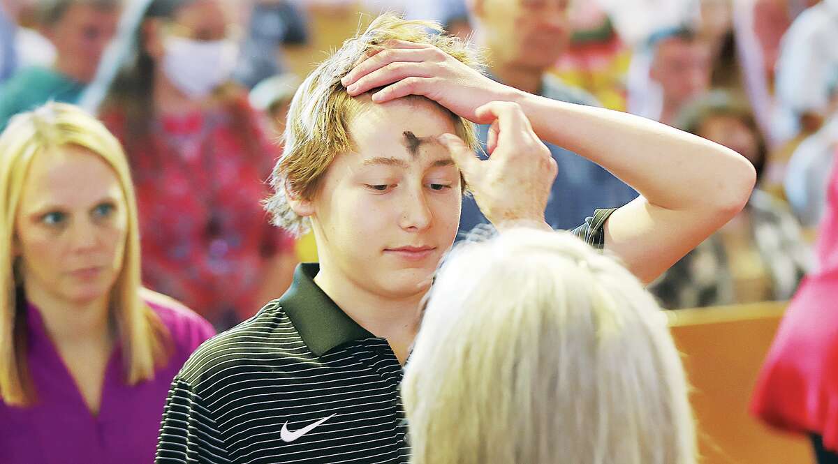 John Badman|Hearst Illinois A teenager holds up his hair to receive the traditional ash cross during the Ash Wednesday Mass at St. Boniface Catholic Church in Edwardsville. About 200 people participated in the noon Mass which included a prayer was said for the people of Ukraine.