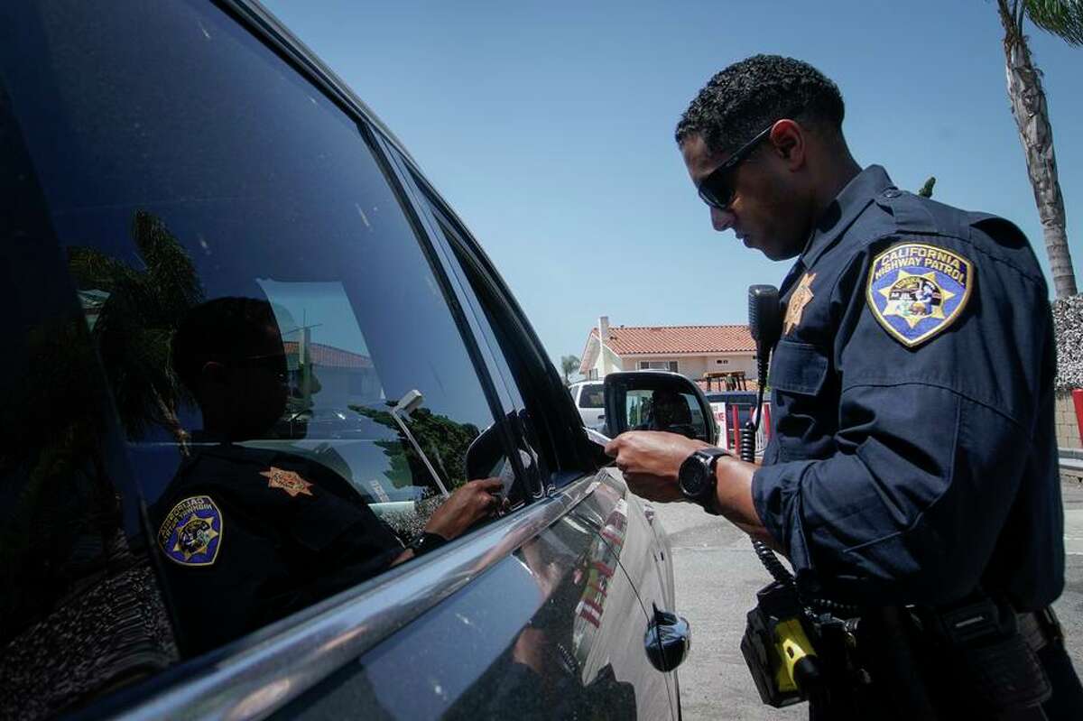 A California Highway Patrol officer stops a motorist for speeding along Interstate 405 on April 23, 2020, in Westminster, Calif. California charges a fee of up to $300 to people who miss deadlines for paying traffic tickets and other fines, though the fees often go uncollected, a new report found.