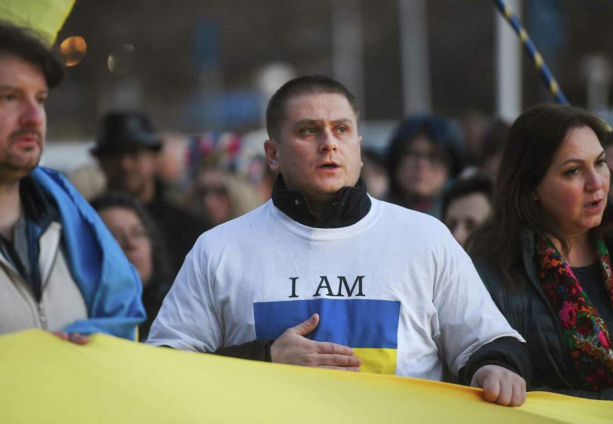 Viktor Lahodyuk, of Stamford, holds his hand over his heart as he sings the Ukraine national anthem with other area Ukranians during a rally and prayer vigil outside City Hall in Norwalk, Conn. on Wednesday, March 2, 2022.