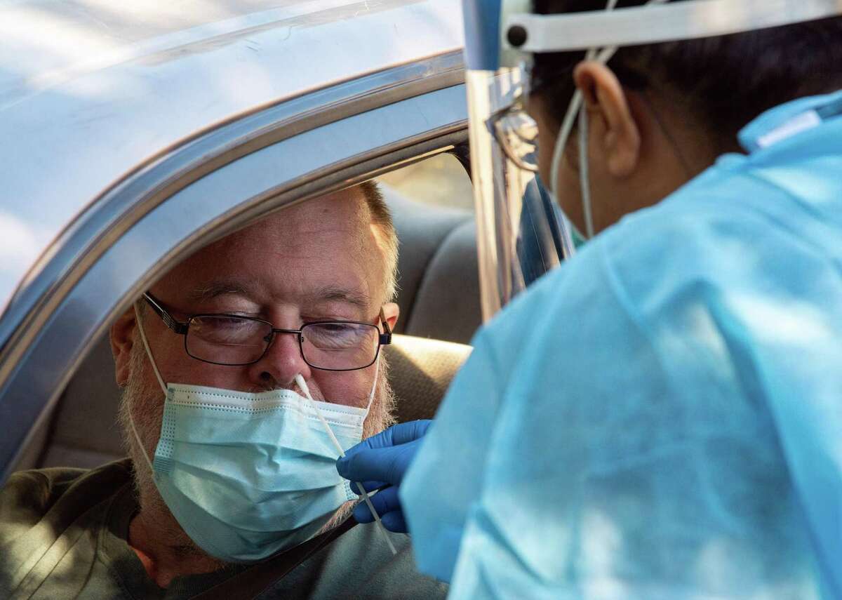 Bill Burke of Rohnert Park receives a nasal swab for a COVID-19 test at Petaluma Health Center in Petaluma, Calif.