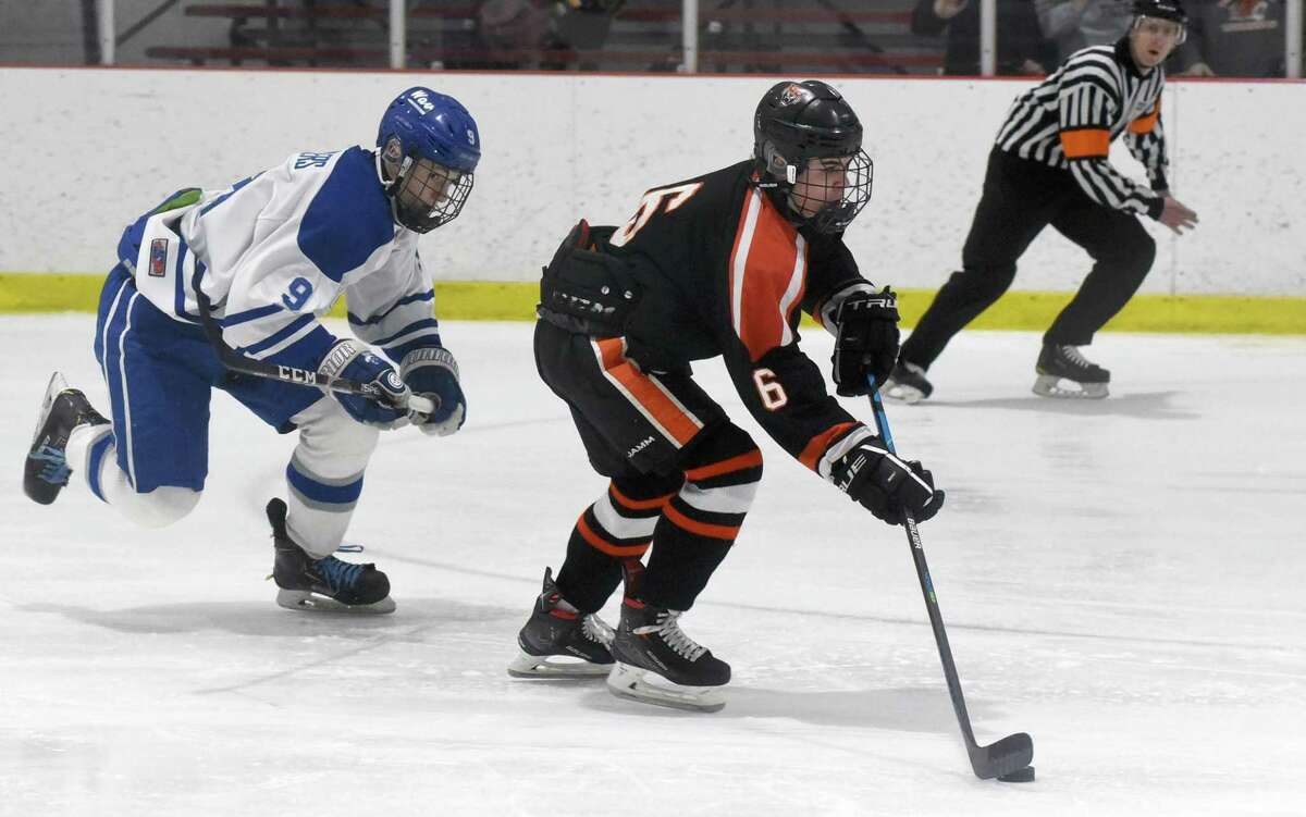 Ridgefield’s Nolan Gartner (6) gets out in front of Darien’s Arthur Devillers (9) for a shot during the FCIAC boys ice hockey semifinals at the Darien Ice House on Wednesday, March 2, 2022.