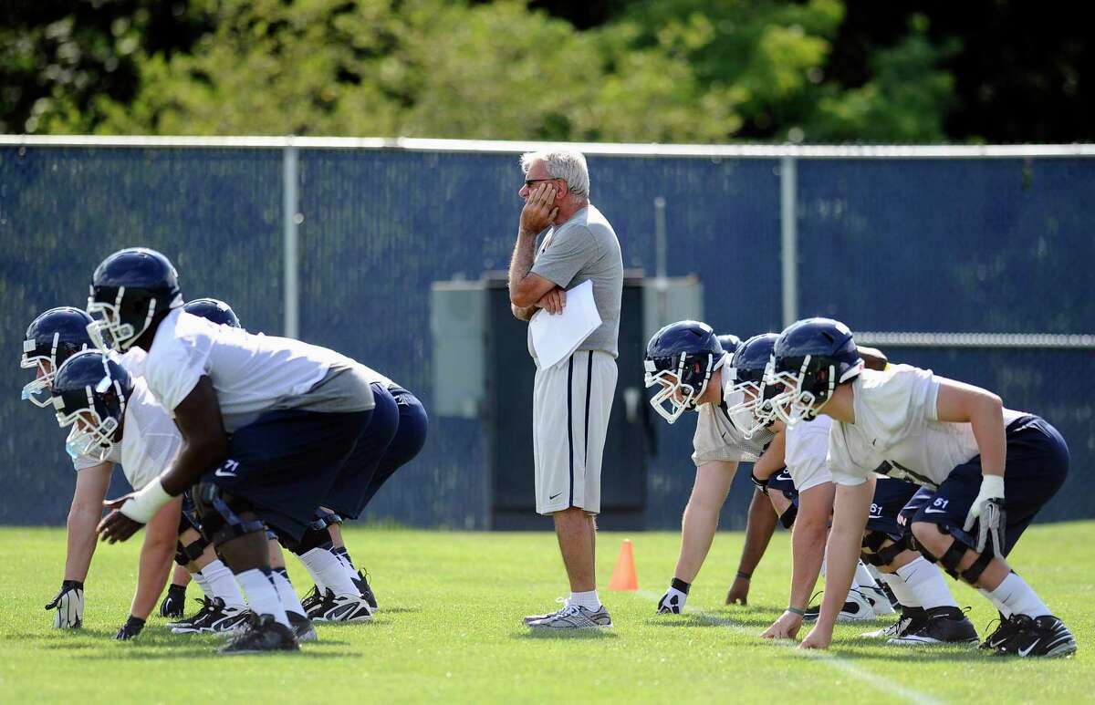 UConn associate coach George DeLeone, center, watches a drill during NCAA football practice in Storrs in 2013.