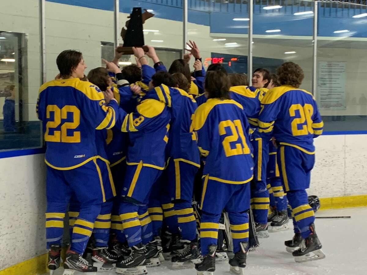 Midland High's hockey team celebrates with the championship trophy after beating Howell 2-1 in double-overtime in Wednesday's Division 1 regional final, March 2, 2022.