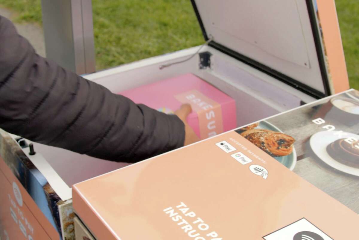 A customer retrieves a box of Bake Sum pastries from a Tortoise robot.