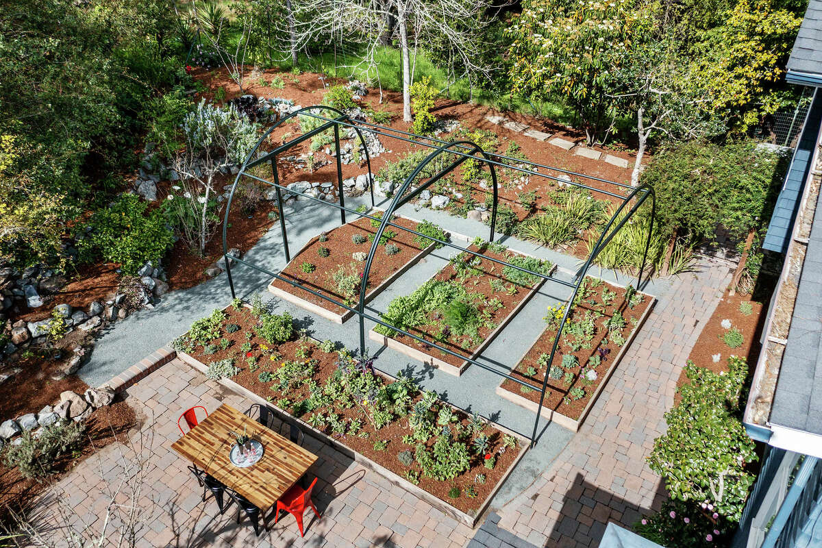The outdoor space with its copious gardens and farm table is a celebration for a home chef. 
