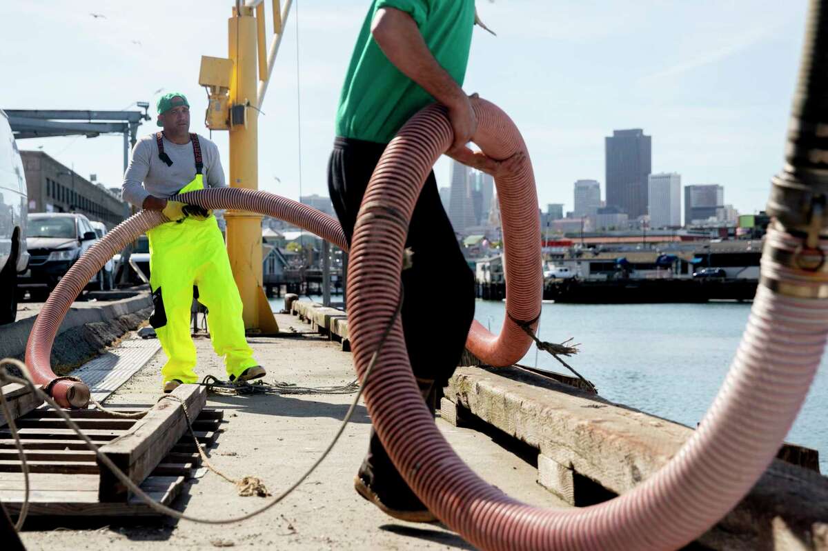 Fisherman Marcus Eaddy (left) and dock employee Michael McGowan maneuver a large hose used to load ice onto Eaddy’s boat, the Midori, at Pier 45 in San Francisco in April 2020 before heading out to fish for salmon ahead of the opening day of the season on May 1. The number of fish off the California coast is expected to be high this year.