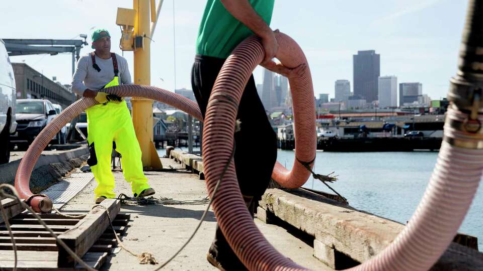 Fisherman Marcus Eaddy, left and dock employee Michael McGowan maneuver a large hose used to load ice onto Eaddy’s boat, the Midori, at Pier 45 in San Francisco in April 2020 before heading out to fish for salmon ahead of the opening day of the season on May 1. The number of fish off the California coast is expected to be high this year.