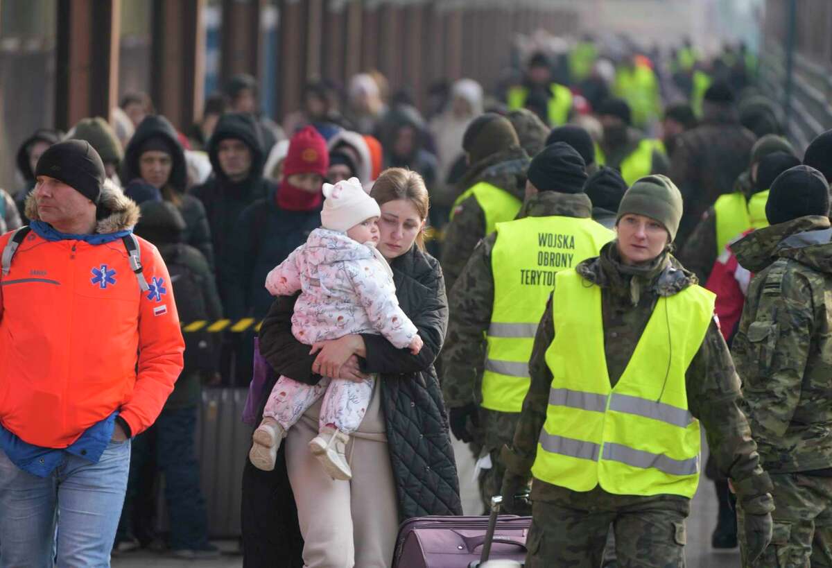 A woman holds a child as she arrives with other displaced Ukrainians after they arrived on a train at the station in Przemysl, Poland, Thursday, March 3, 2022. More than 1 million people have fled Ukraine following Russia's invasion in the swiftest refugee exodus in this century, the United Nations said Thursday.