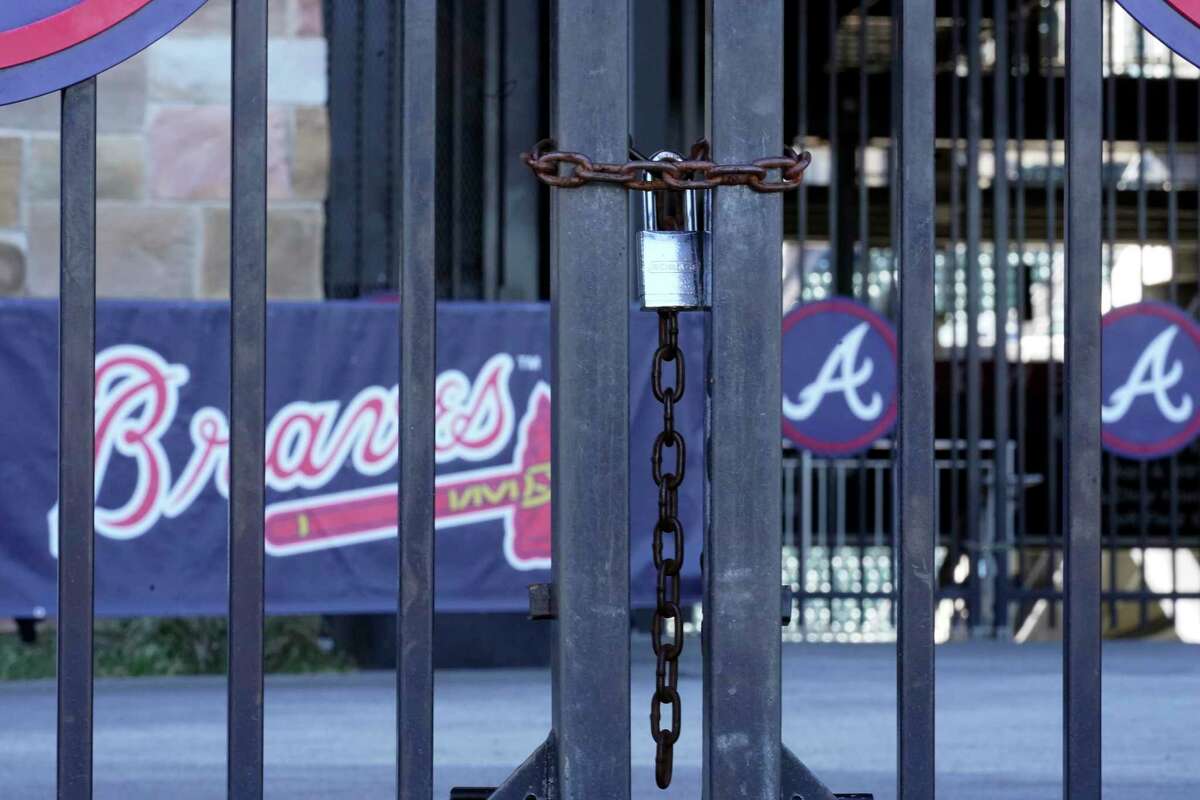 Locked gates are shown at Truist Park home of the Atlanta Braves baseball team Wednesday, March 2, 2022, in Atlanta. MLB commissioner Rob Manfred has canceled the first two series for each of the 30 teams, cutting each club's schedule from 162 games to likely 156 at most. (AP Photo/John Bazemore)