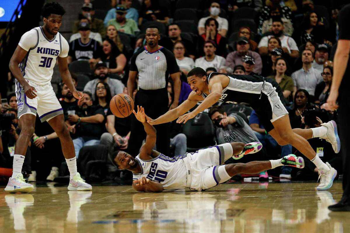 San Antonio Spurs forward Keldon Johnson (3) lunges over Sacramento Kings forward Harrison Barnes (40) to take control of a loose ball during the first half at AT&T Center, Thursday, March 3, 2022 in San Antonio, Texas.