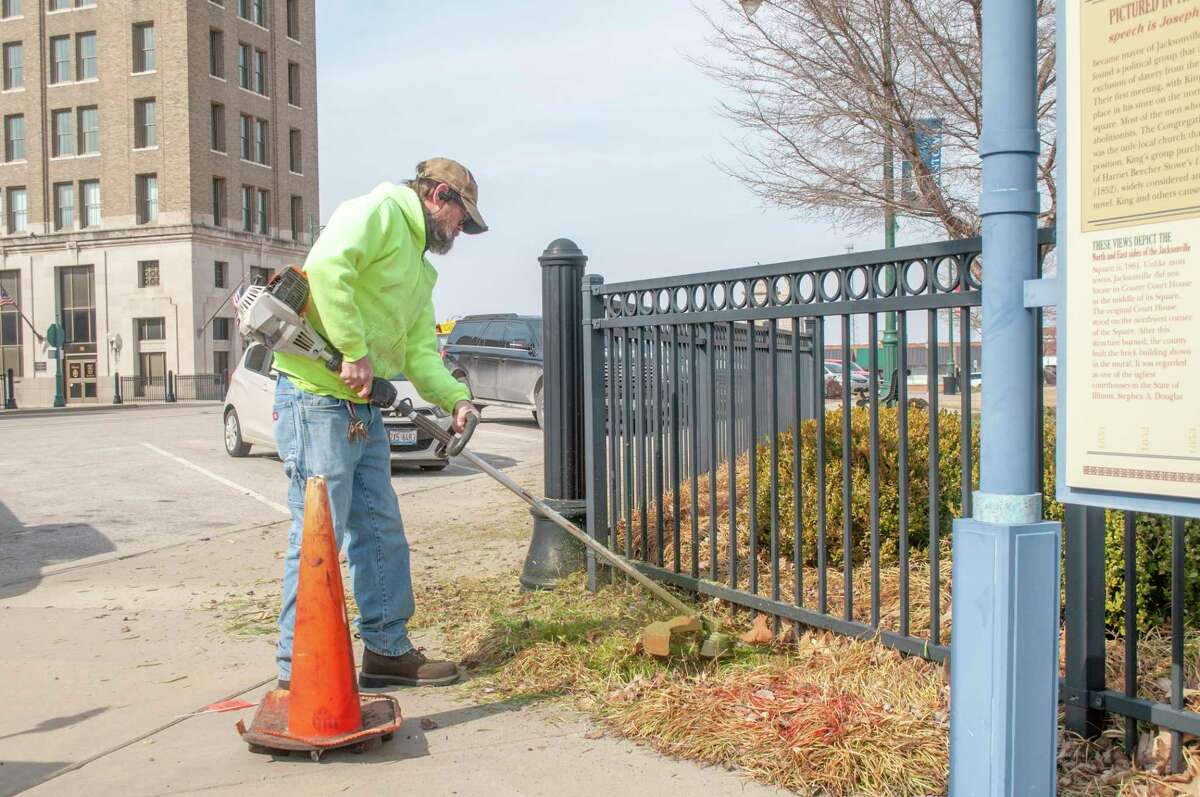City of Jacksonville employee Mike Brant uses a weed trimmer Friday to spruce up Jacksonville's downtown square as spring weather approaches. 