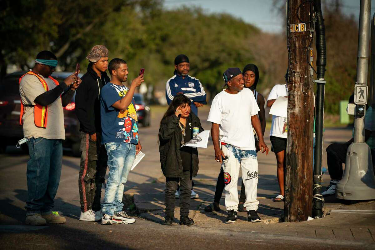 People crowd around the corner where Dimitri Reeves is performing, Thursday, March 3, 2022, in Houston. Between songs, Reeves takes time urging people to love one another, and says his goal is to spread positivity and love in the world. 