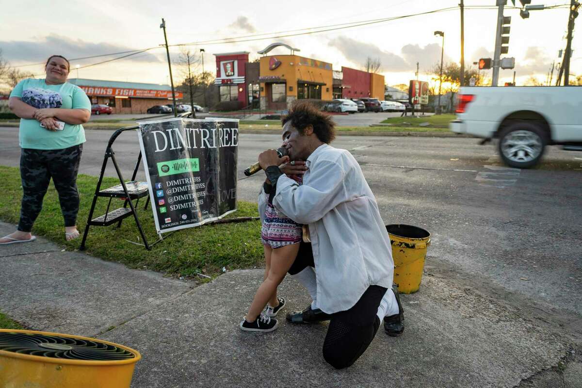 Ophelia Hudson, 4, runs up to Dimitri Reeves for a mid-performance hug, Thursday, March 3, 2022, in Houston. Ophelia’s mother, Allison Lopez, said this is the fifth time the family has caught Reeves perform in person. They started following his Instagram, and now if they see he is performing close by, they try to make it in time. What keeps them coming back? “Just the positivity,” said Lopez.
