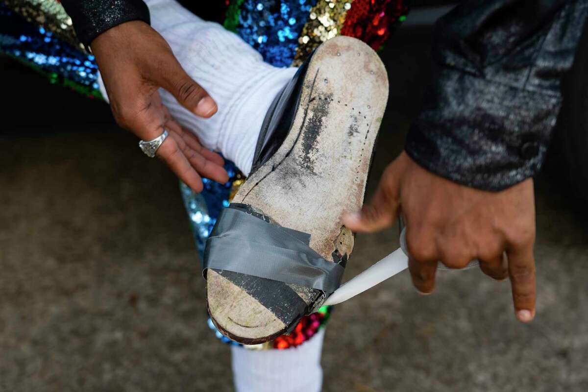 Dimitri Reeves duct tapes a pair of shoes before performing, Thursday, March 3, 2022, in Houston. 