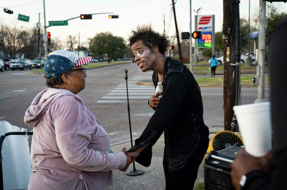 Dimitri Reeves talks to a woman who watched his performance at the corner of Lockwood Drive and Calvalcade Street, Thursday, March 3, 2022, in Houston. He urges people to love one another, and his goal is to spread positivity and love in the world, he says.