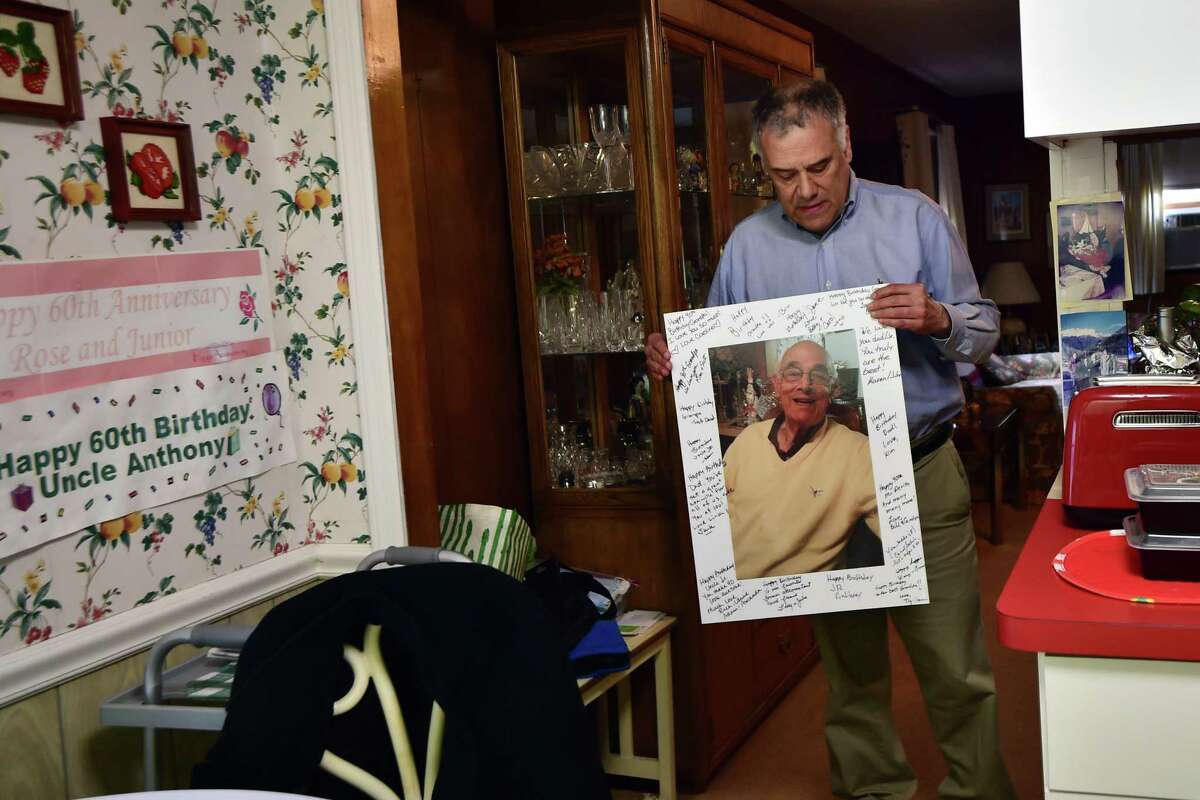 Anthony DeVito III holds up a photo of his father Anthony DeVito Jr. at his home in Darien, Conn., on Thursday February 24, 2022. Anthony lost his dad Anthony DeVito Jr. from COVID-19 at age 92 and his brother Jack died from COVID-19 as well at age 60.