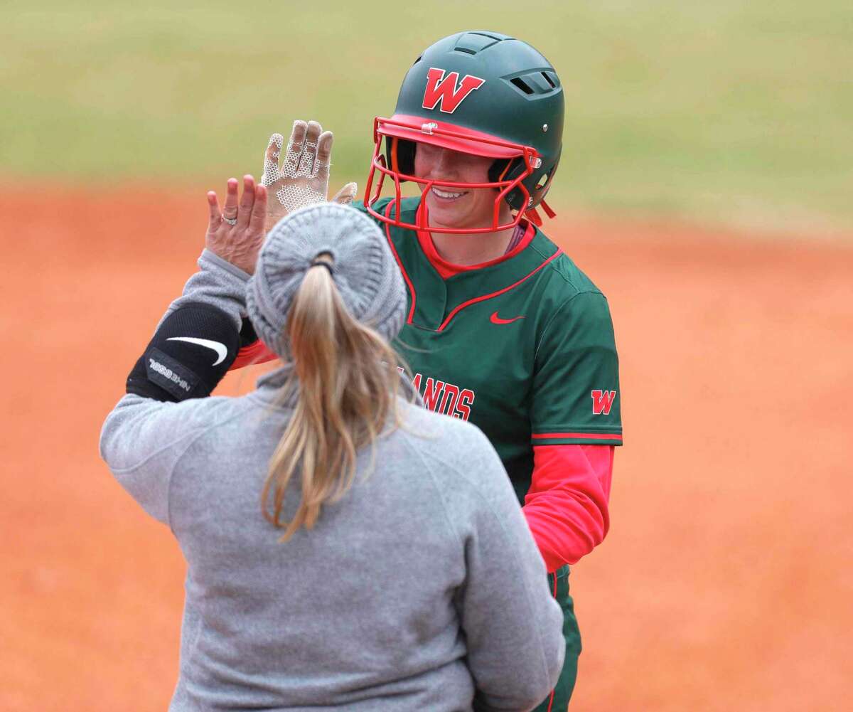 Alannah Leach #1 of The Woodlands gets a high-five after reaching first on an error in the second inning of a non-district high school softball game at The Woodlands High School, Friday, Feb. 25, 2022, in The Woodlands.
