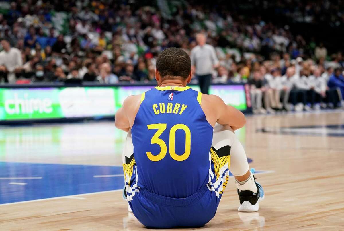 Guard Stephen Curry, who scored 21 points in 40 minutes, takes a seat during the Warriors’ game against the Mavericks Thursday in Dallas.