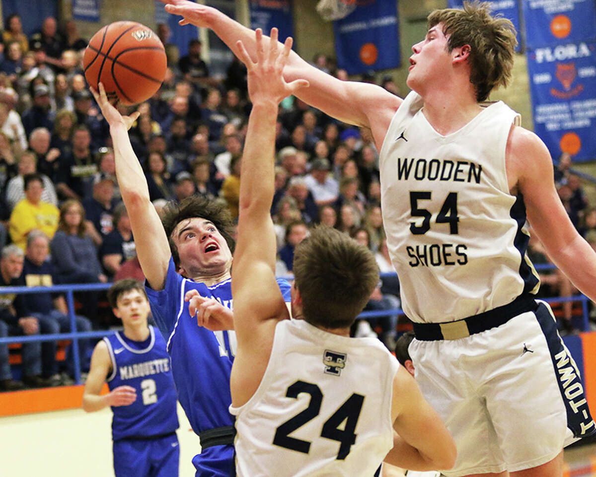 Marquette Catholic's Owen Williams shoots over Teutopolis' Caleb Siemer (54) and Mitch Althoff (24) last Tuesday in a Class 2A sectional semifinal at Flora.