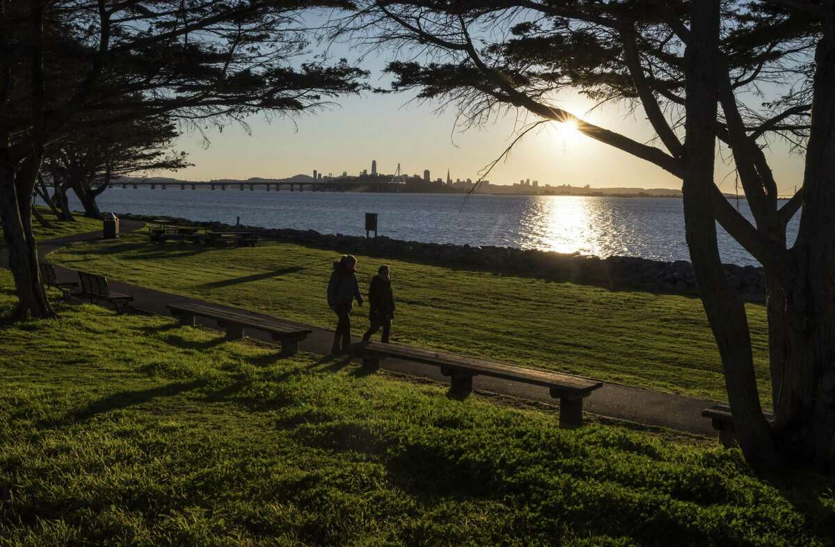 A couple walks along the shoreline at the Emeryville marina in February. After a brief spell of rain, Bay Area weather is set to return to the dry conditions that have prevailed since the new year.