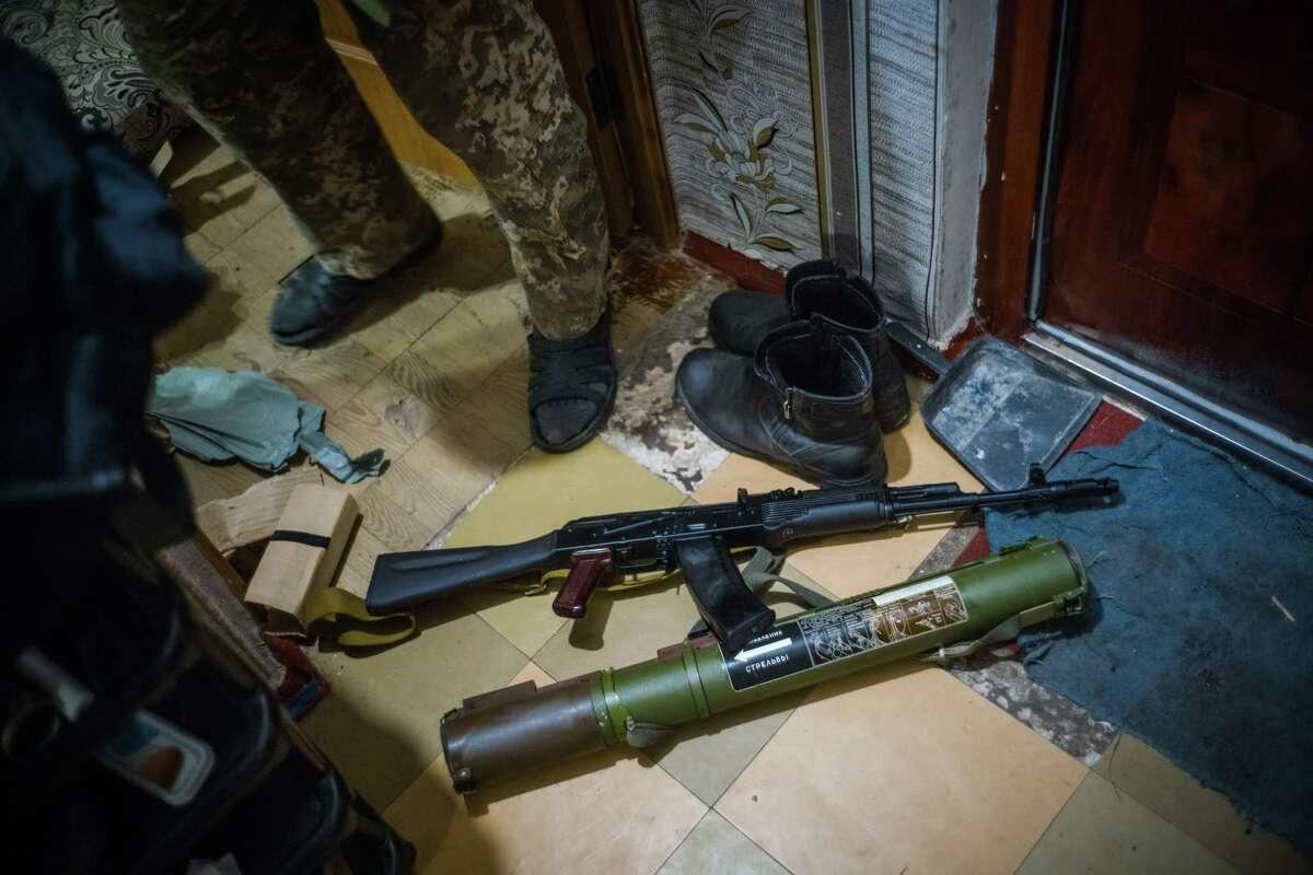 Oleksandr, a retired Ukrainian military officer in Bila Tserkva who declined to give his last name and lives in a building damaged by bombing, displays weapons he says he plans to use against Russian troops.