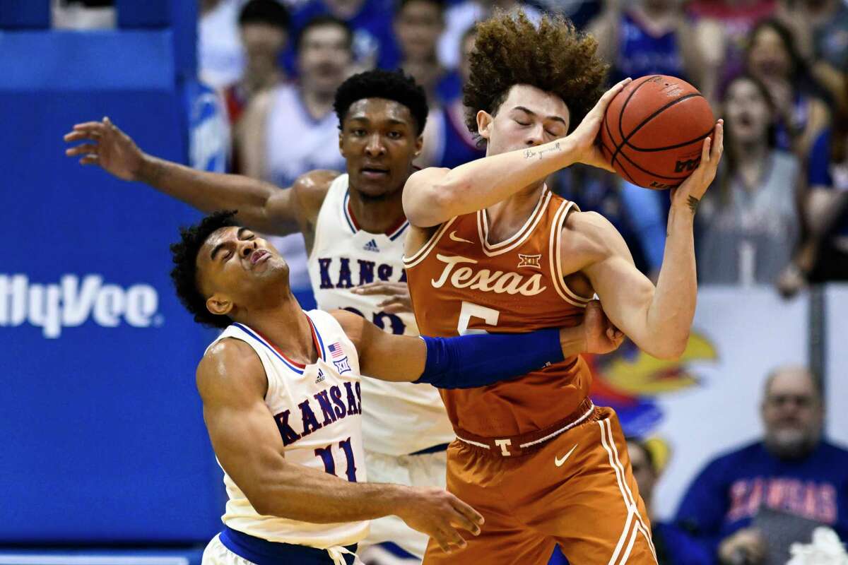 Texas guard Devin Askew (5) and Kansas guard Remy Martin (11) battle for the ball during the first half of an NCAA college basketball game in Lawrence, Kan., Saturday, March 5, 2022. (AP Photo/Reed Hoffmann)