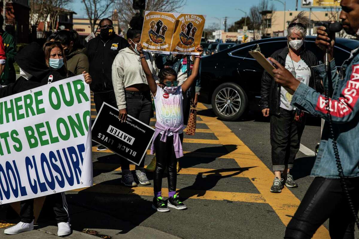 Second-grader Demi Johnson holds a sign during a protest against Oakland Unified School District’s plan to close schools outside Roots International Academy in Oakland, Calif. on Saturday, March 5, 2022. The ACLU is asking California Attorney General Rob Bonta to weigh in on the controversy.