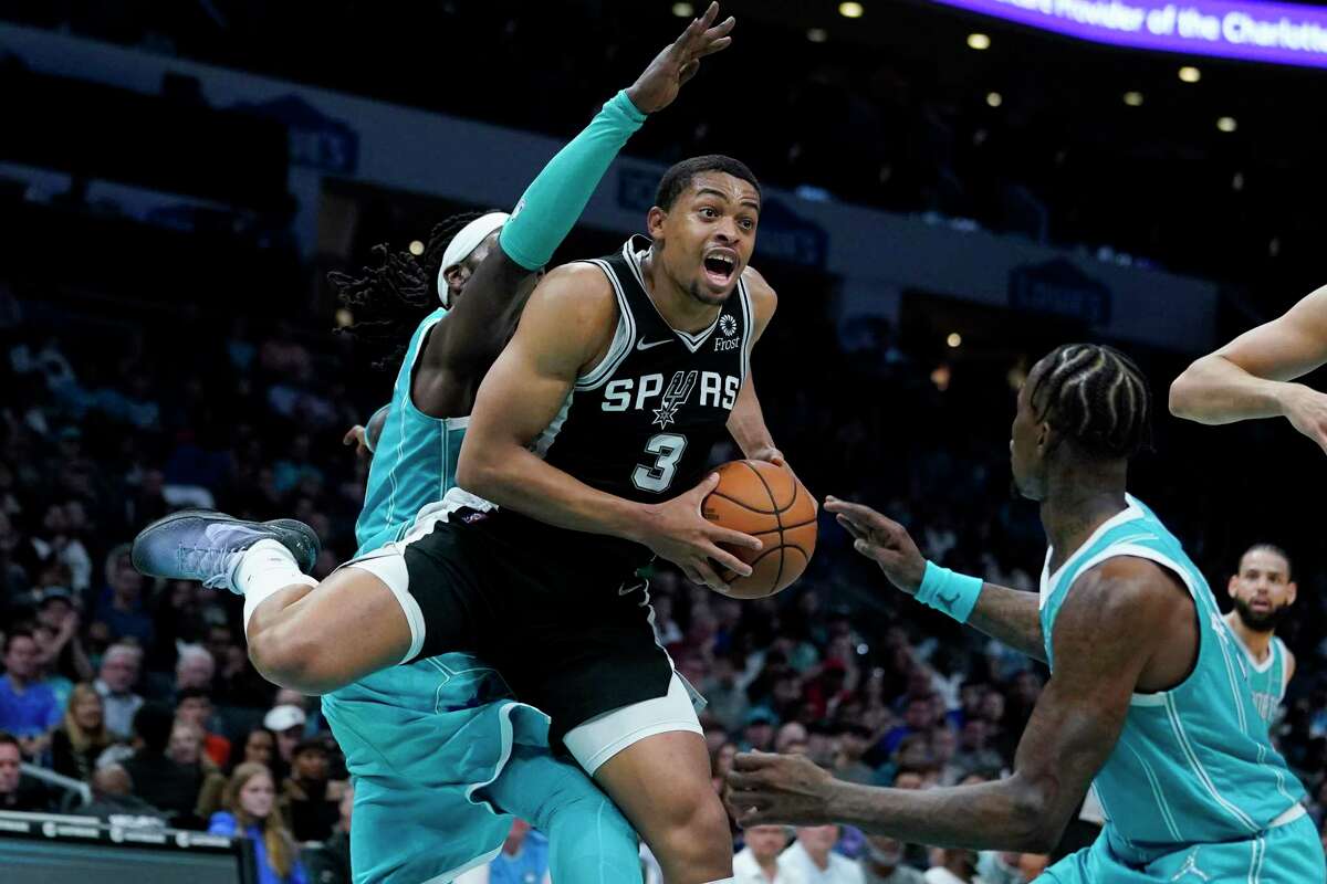 Spurs forward Keldon Johnson (3) drives to the basket between Hornets center Montrezl Harrell and guard Terry Rozier during the second half Saturday, March 5, 2022, in Charlotte, N.C.
