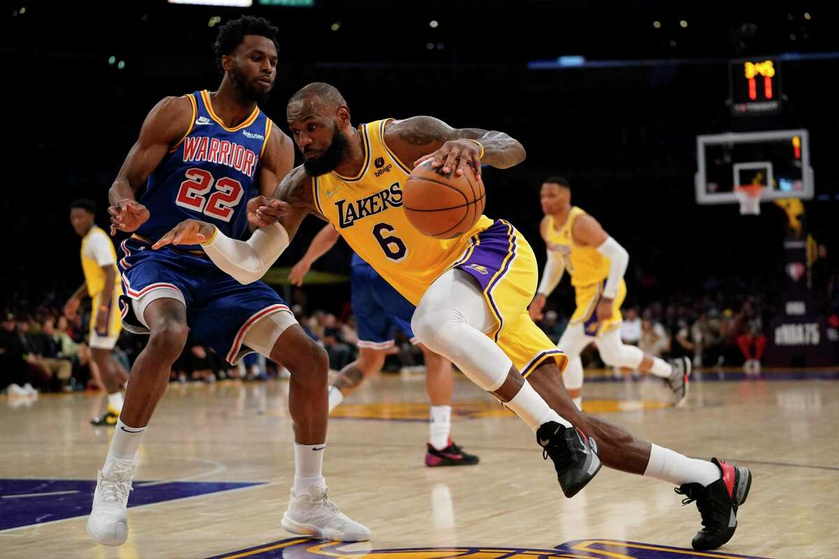 Los Angeles Lakers forward LeBron James (6) drives against Golden State Warriors forward Andrew Wiggins (22) during the first half of an NBA basketball game in Los Angeles, Saturday, March 5, 2022. (AP Photo/Ashley Landis)
