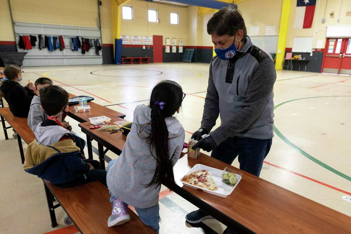Enrique Moncada helps a student open her milk during lunch. Moncada is the head custodian at Pearce Elementary, and he has worked for the district for 30 years.
