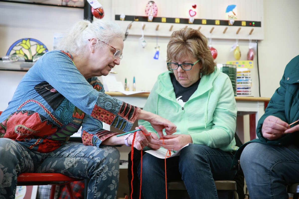 Georgia Brown helps one of her students Sherry Boer in threading yarn around hook during a crochet class Saturday at the Kaleva Art Gallery.
