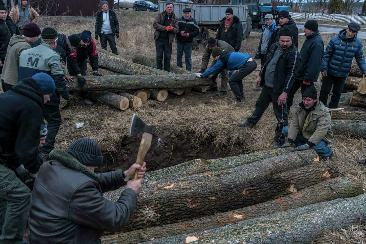 Ukrainians, ordinary men and women, chop wood as they build a bunker in preparation to fight Russian troops in Hushchyntsi, Ukraine, on Feb. 27.