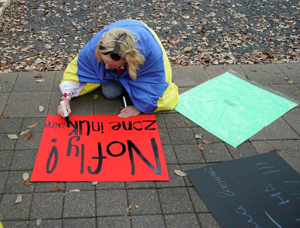 A woman makes a sign during a protest with the Consulate General of Ukraine calling for a no-fly zone to be instituted over the Eastern European country at City Hall on Sunday, March 6, 2022 in Houston.