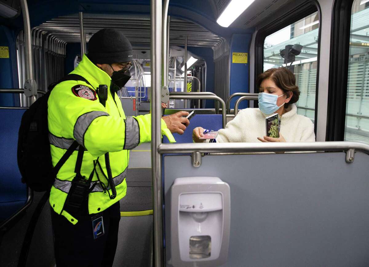 Metropolitan Transit Authority fare inspector Eduardo Botello scans Alma Cato’s Q Card on the Silver Line Thursday, Feb. 24, 2022, in Houston. Cato rides a park and ride bus and Silver Line back and forth to work.