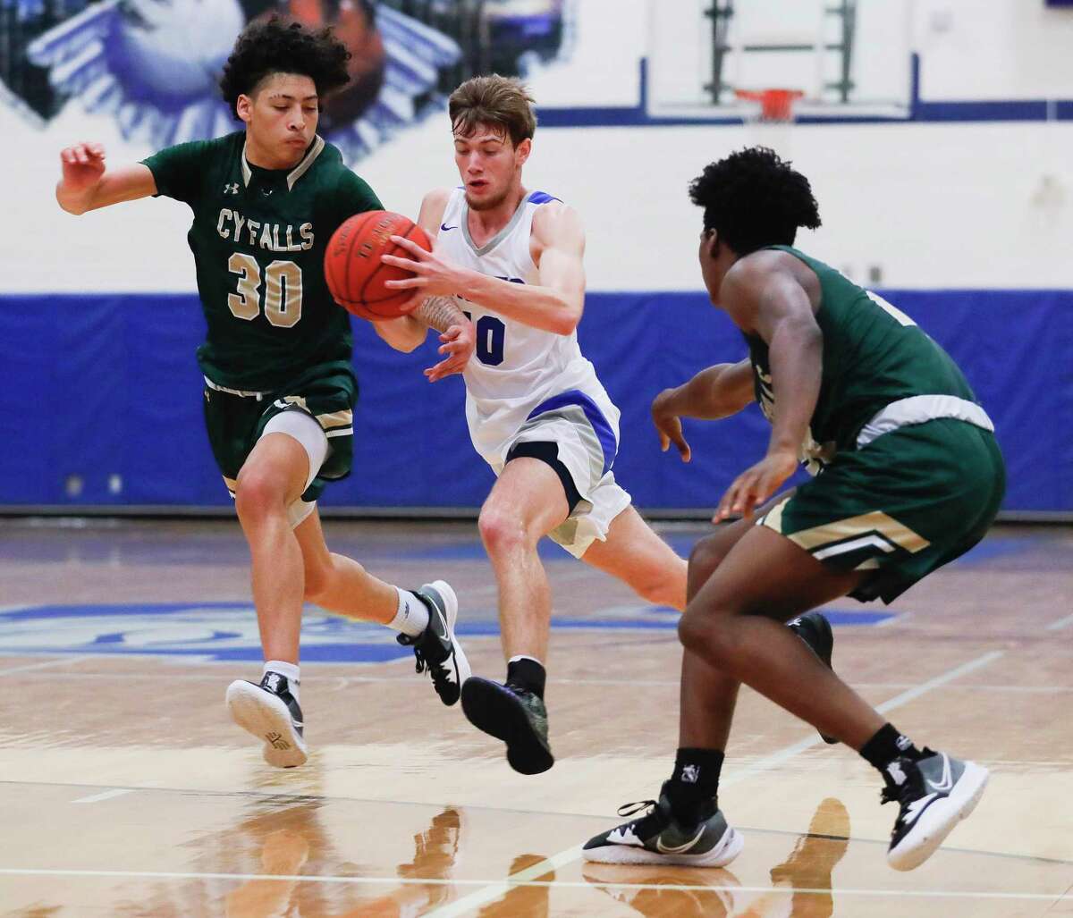 New Caney point guard Samuel Brandon (10) splits a pair of Cypress Falls defenders during a high school basketball game at New Caney High School, Tuesday, Dec. 28, 2021, in New Caney/