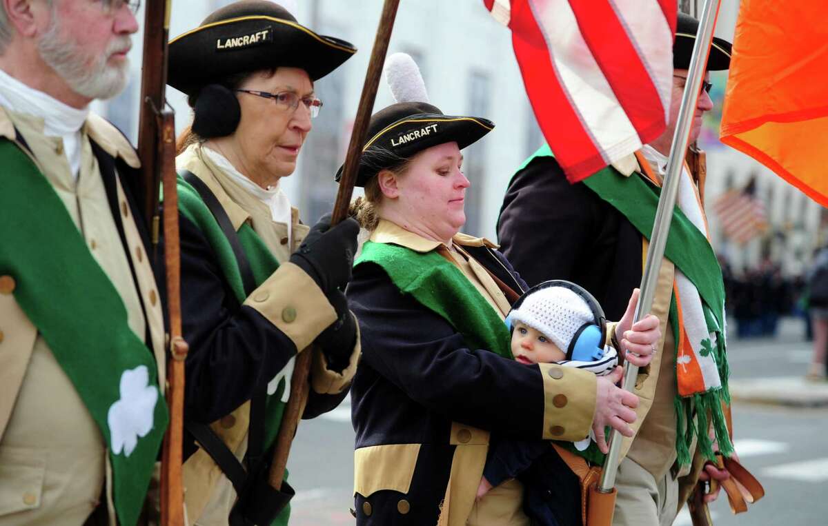 Alissa Roland, with the Lancraft Fife and Drum Corp, holds her son Chapin, 10 months, as she takes part in the 27th annual St. Patrick's Day Parade in downtown Stamford on Saturday, March 5, 2022.