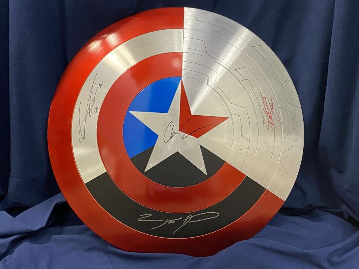 The shield to be raffled off by the local Make-A-Wish chapter incorporates the logos of several Marvel Universe characters.
