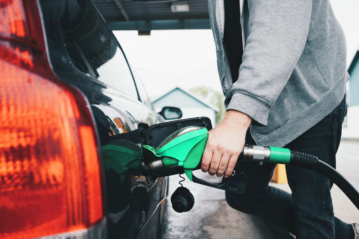 A person filling their car with gas. 