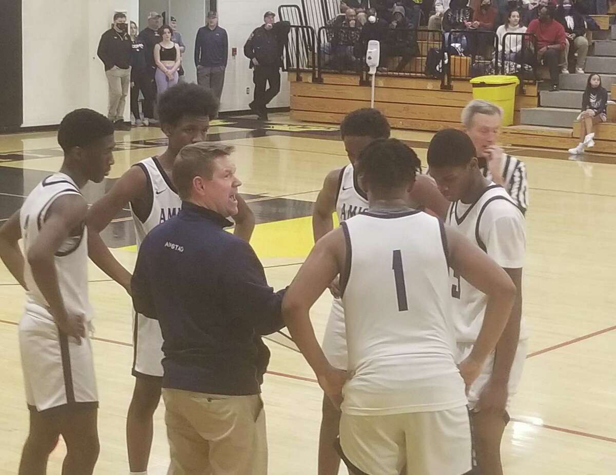 Amistad boys basketball coach Ryan Ott (in blue) speaks to his players during the fourth quarter of their 65-62 win over Amity in the CIAC Division II state tournament on Monday in Woodbridge.