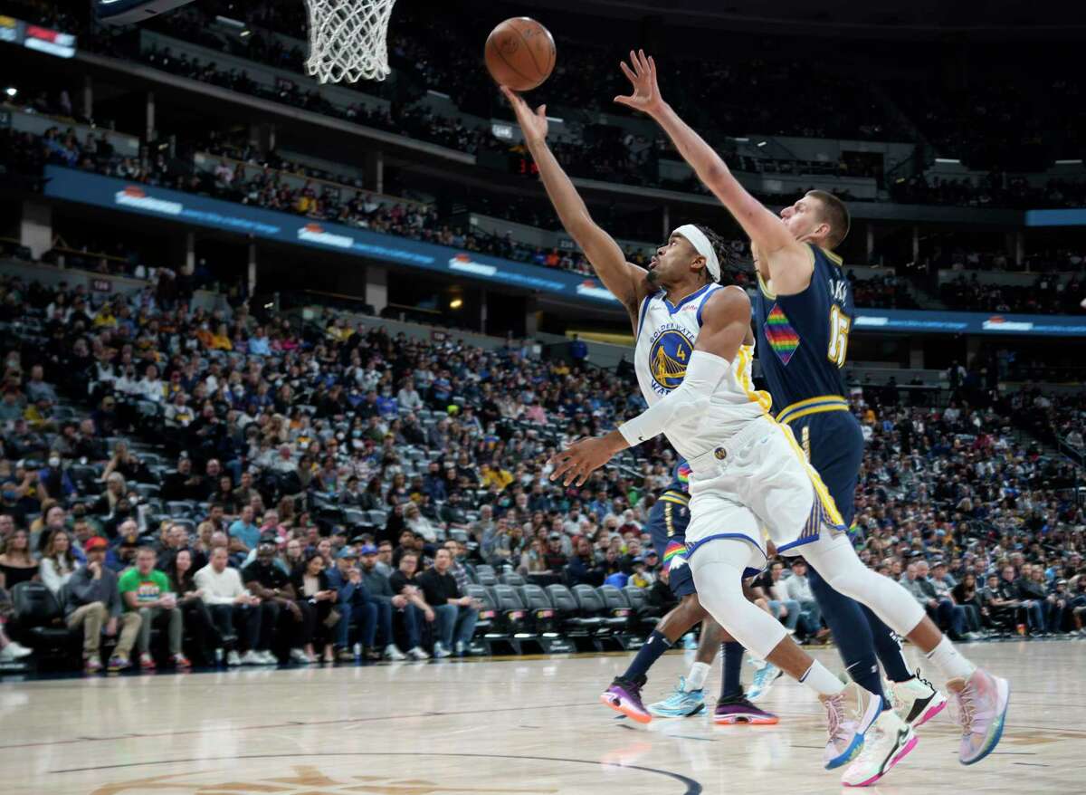 Golden State Warriors guard Moses Moody (4) drives to the basket as Denver Nuggets center Nikola Jokic defends in the first half of an NBA basketball game Monday, March 7, 2022, in Denver. (AP Photo/David Zalubowski)