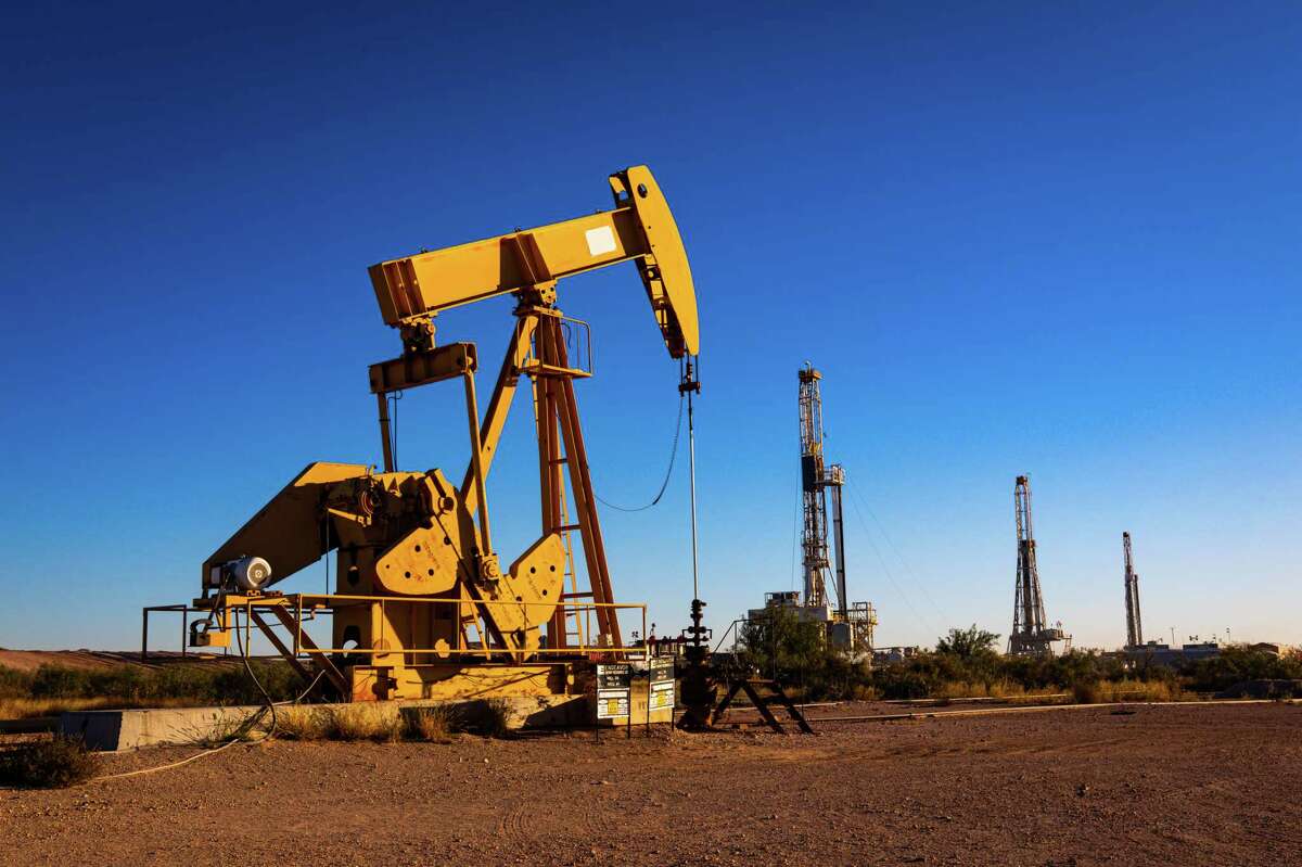 A pumpjack and three drilling rigs photographed in this October 2021 file photo in Midland.