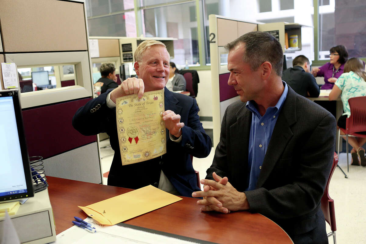 Mark Phariss holds up the license for his upcoming marriage with Victor Holmes after it was handed to them at the Bexar County Marriage License Office in the Paul Elizondo Tower in San Antonio on Friday, Sept. 25, 2015.